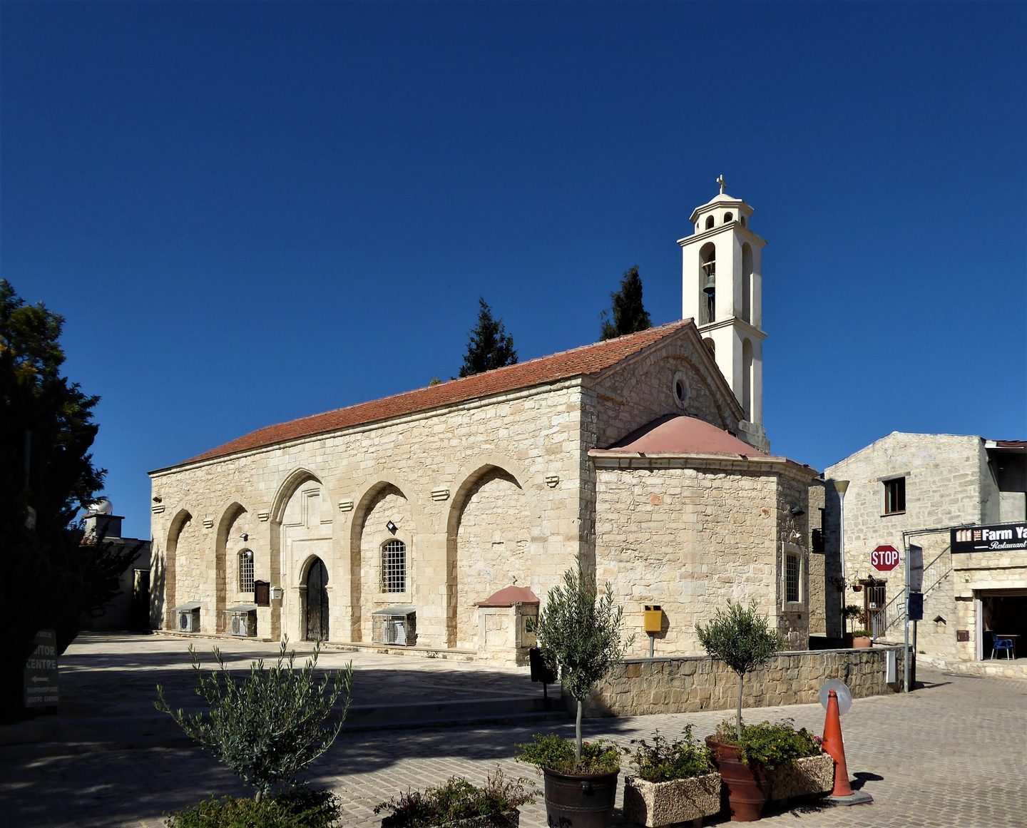The arcaded stone church of Panagia Evangelistria in Kathikas under a deep blue sky