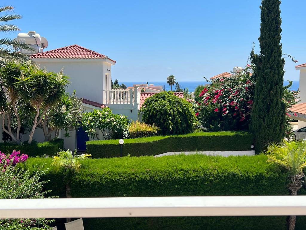 Clipped hedges and bougainvillea framing a strip of blue sea between the rooftops