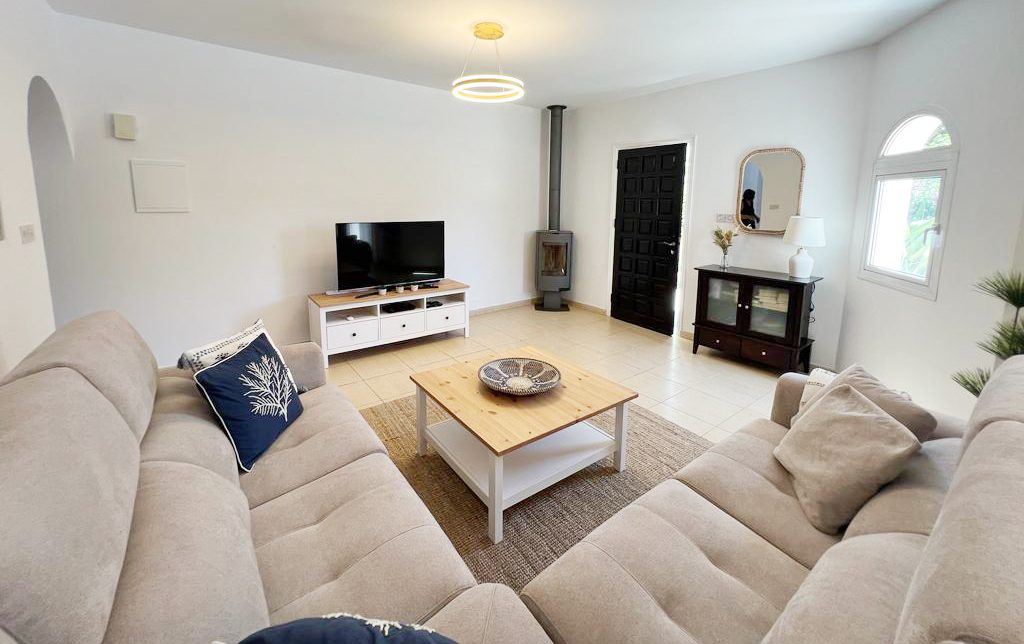Bright living room with two deep sofas facing a wood-burning stove and television