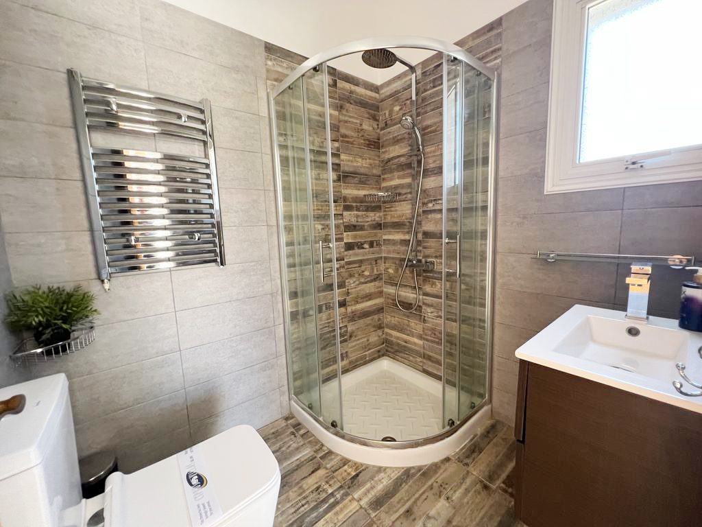 Shower room with curved corner cubicle, rainfall head and timber-effect tiling
