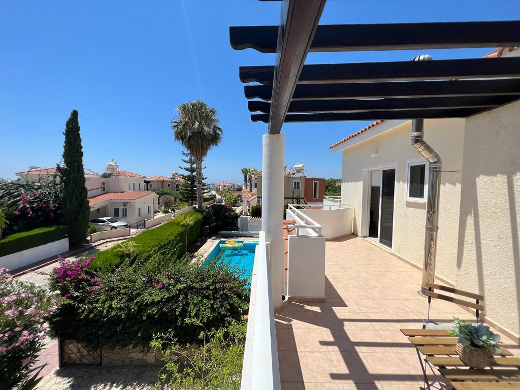 Tiled upper terrace under a dark wooden pergola overlooking the pool and neighbouring villas