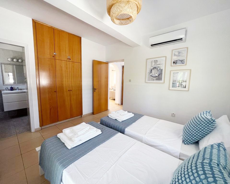 Twin bedroom with wooden fitted wardrobes and a doorway through to its en-suite bathroom