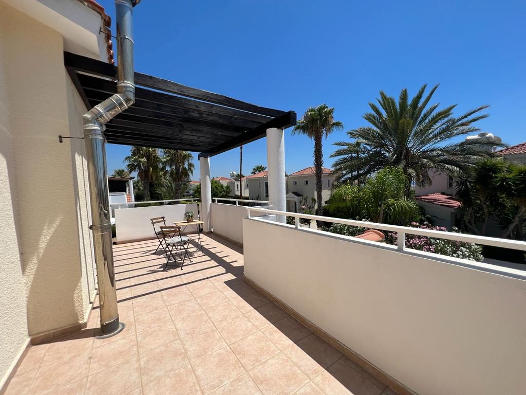 Long upper terrace under a dark pergola with views over palms and terracotta roofs