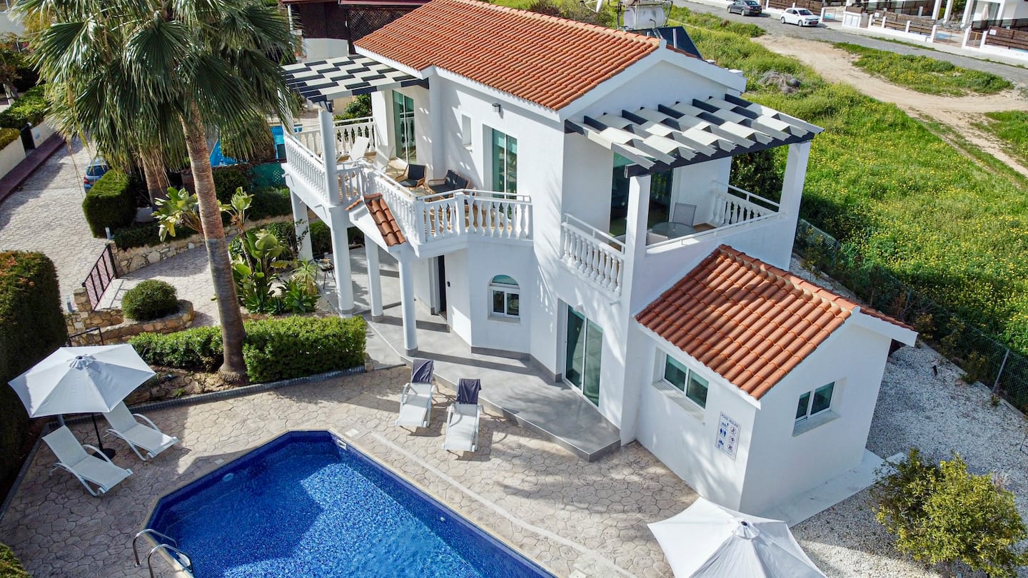 Aerial view of the white villa, its terracotta roof, pool terrace and mature garden