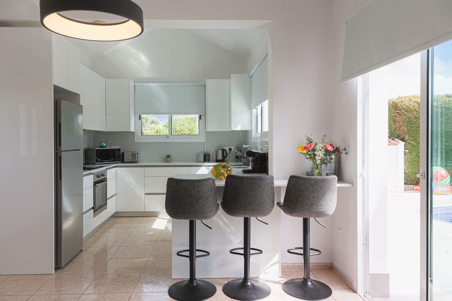 Three grey stools at the kitchen breakfast bar beside doors to the terrace