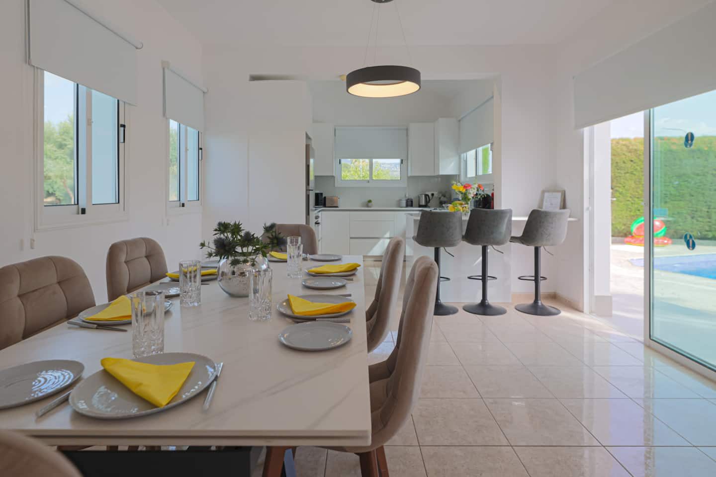 Marble dining table laid for six between the kitchen bar and the pool doors
