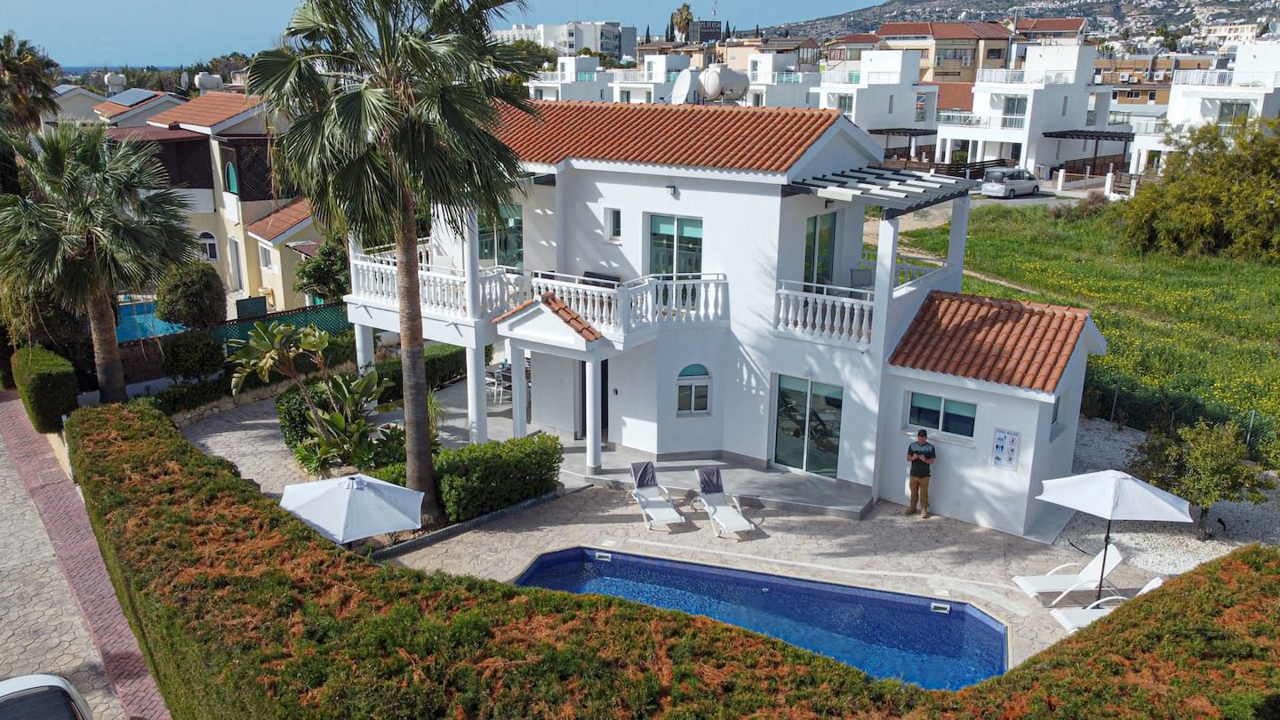 The villa from above, terracotta roof and pool set against Coral Bay rooftops and hills