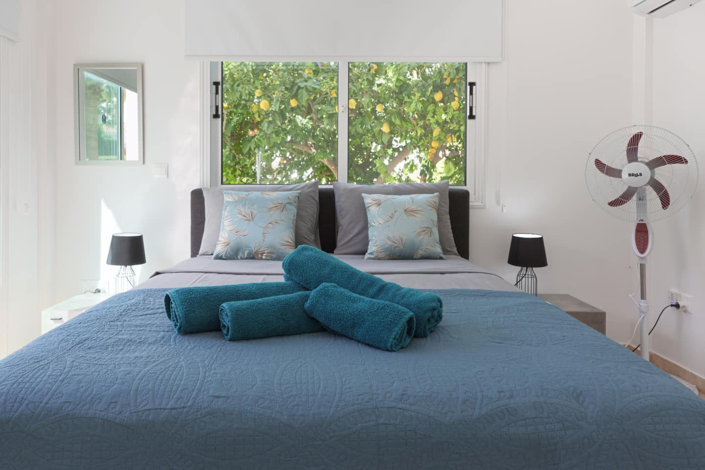 Ground-floor double bed below a window filled with a fruiting lemon tree