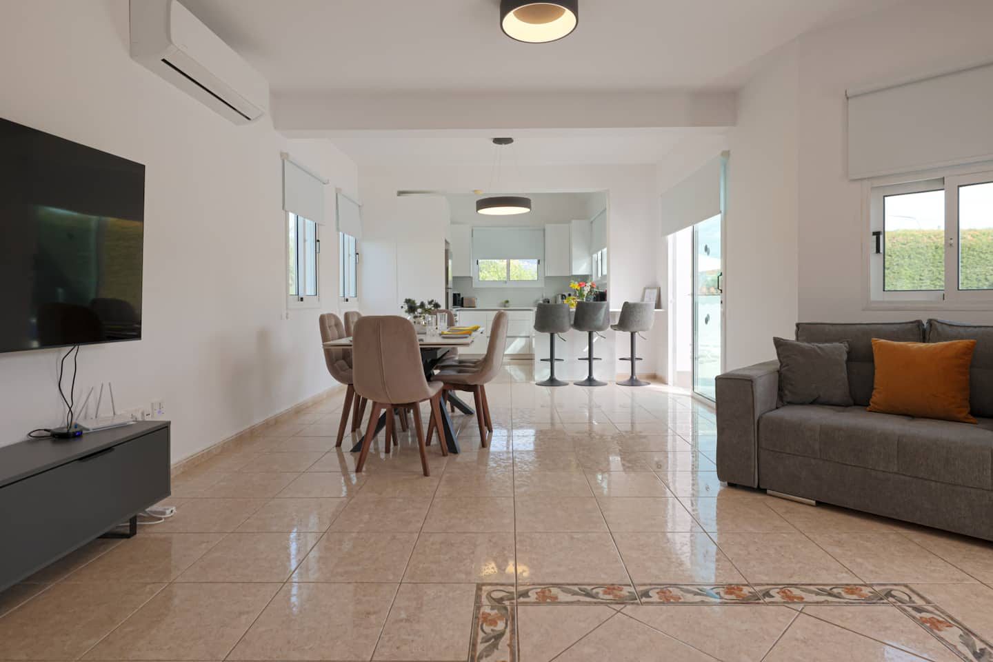Open-plan living room with wall-mounted television, sofa and dining table beyond