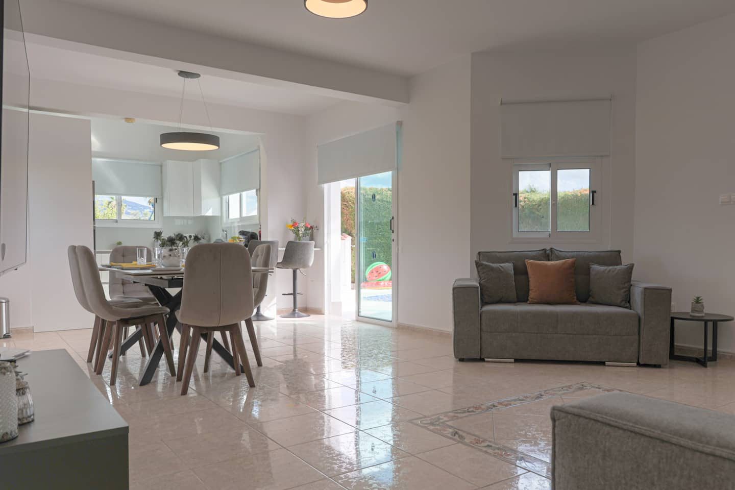 Lounge sofa beside sliding doors to the pool, dining table and kitchen behind