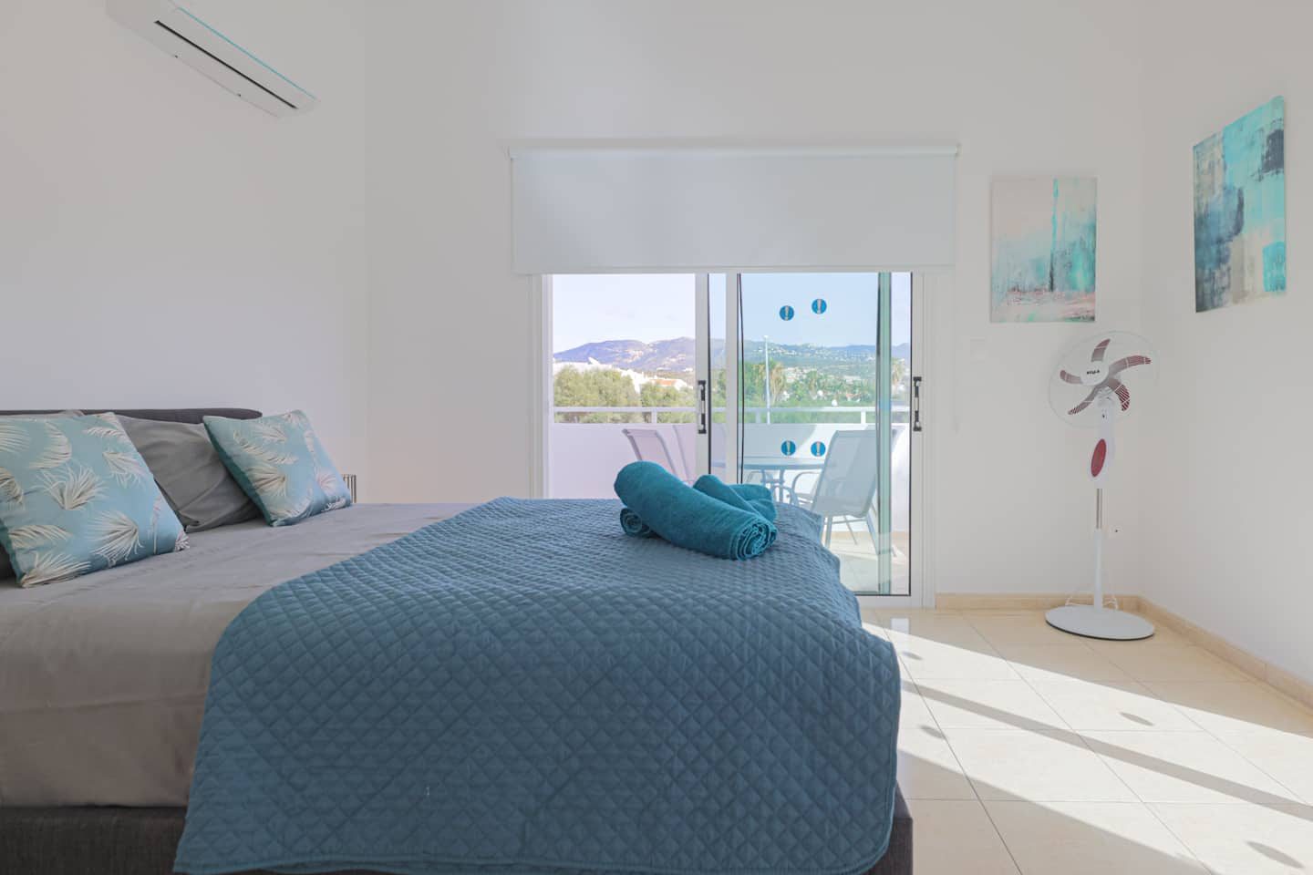 Master bedroom with double bed and balcony doors framing the inland hills