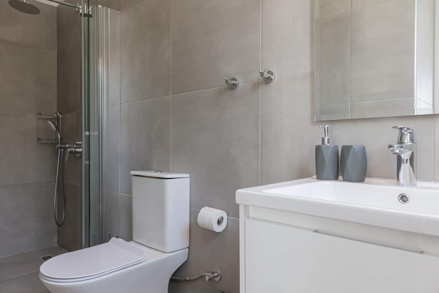 En-suite shower room with folding glass screen, white basin unit and mirrored cabinet